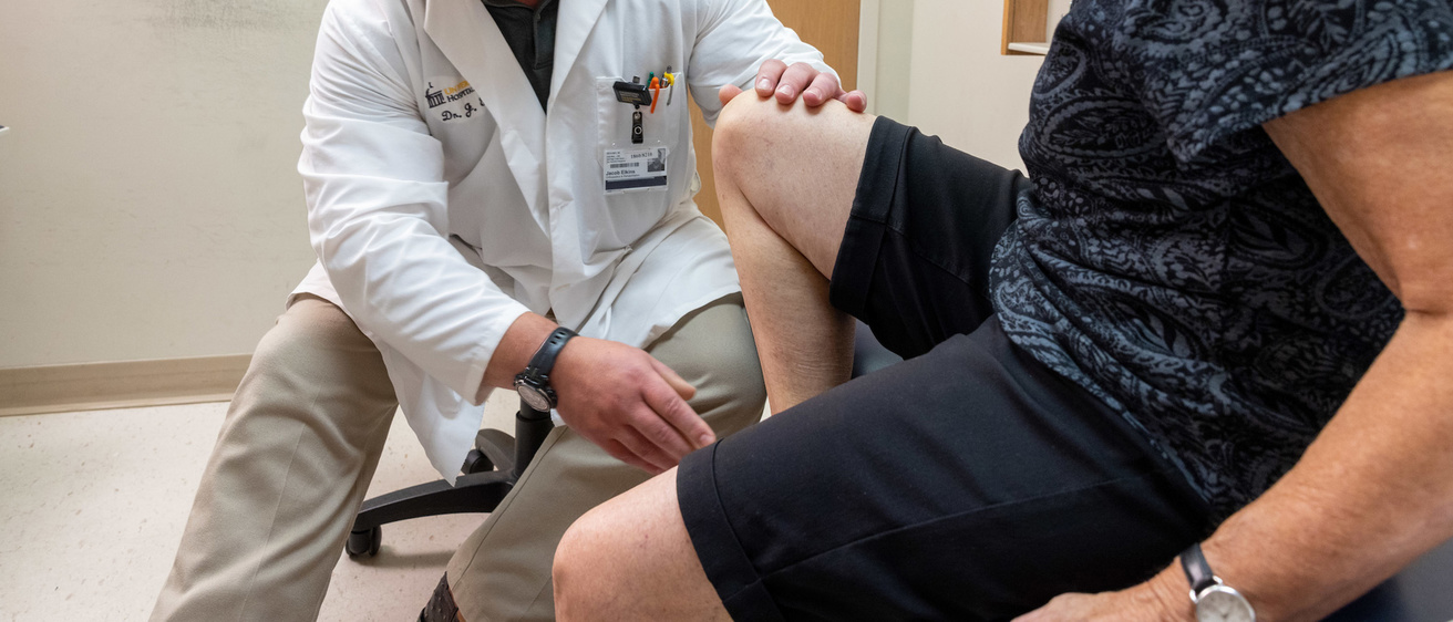 Jacob Elkins examines the knee of a patient